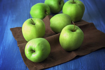 Green apples on wooden table with napkin, closeup