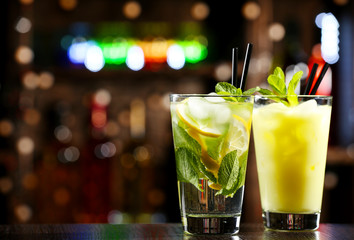 Glasses of cocktails in bar on bright blurred background