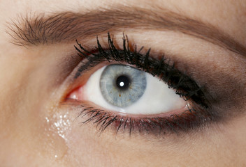 Eye of young woman with tear drop close up