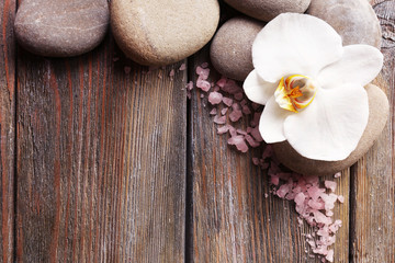 Spa stones and orchid flower on wooden background