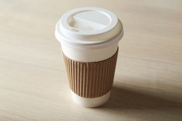 Paper cup of coffee on wooden background