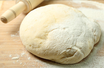 Dough on cutting board with rolling pin close up
