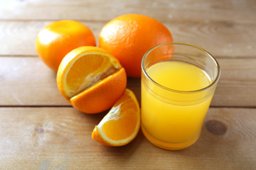 Glass of orange juice and slices on wooden table background