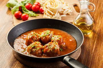 Meatballs with tomato sauce on black pan