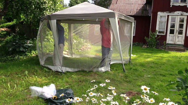 men fix transparent insects screen to metal arbor construction
