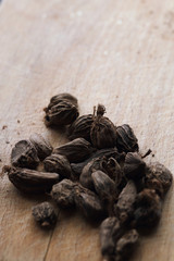 Seeds of black cardamom on the wooden background