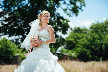 Fototapeta na wymiar Beautiful bride outdoors. Bride holding wedding bouquet outside