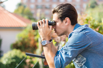 Fototapeta na wymiar Young man looking through binocular searching outside