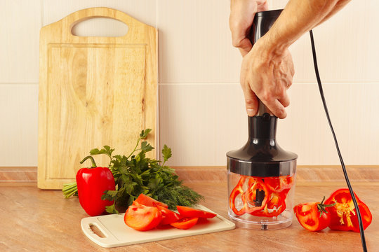 Hands cook are going to shred red pepper in a blender
