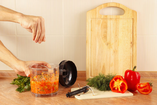 Hands of chef salt cooked vegetable salsa in a blender