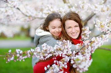 Fototapeta premium Mother and her child in blooming cherry garden