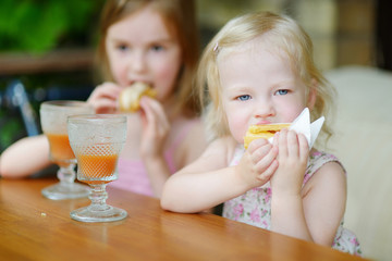 Two sisters drinking juice and eating pastries