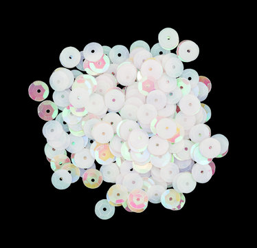 Rose and white hued sequins on a black background.