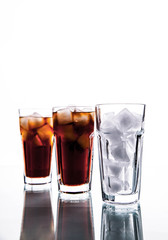 three glasses of cola and ice on a white background. soft drinks