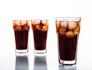 three glasses of cola and ice on a white background. soft drinks