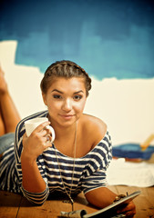 Portrait of female painter lying on floor near wall after