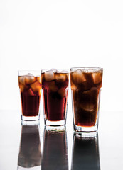 three glasses of cola and ice on a white background. soft drinks