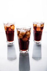 three glasses of cola and ice on a white background. soft drinks