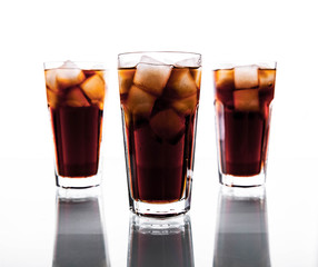 three glasses of cola and ice on a white background. soft drinks