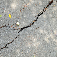 Obraz premium Old wet worn and cracked asphalt with cracks