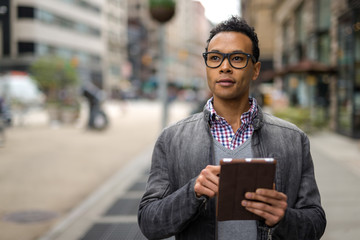 Young African Asian man in New York City using tablet pc