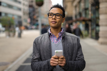Young African Asian man in New York City texting cell phone