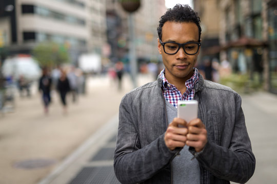 Young African Asian Man In New York City Texting Cell Phone