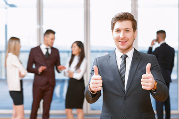 Young business man standing in front of his co-workers  talking