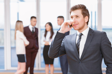 Young business man standing in front of his co-workers  talking