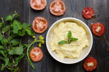 Mashed potato in the bowl with vegetable on wooden background