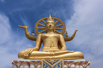 Golden Buddha statue in Thailand with blue sky background