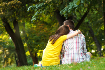 Naklejka premium Rearview of a young couple sitting in park.