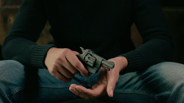 Young man sitting on a sofa with a revolver 