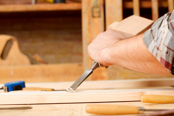 Closeup of a carpenter working with chisel and carving tools.