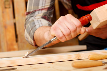 Closeup of a carpenter working with chisel and carving tools.