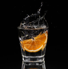 Slice of lemon splashing into a glass 