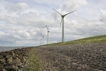 Fototapeta na wymiar Modern windmills nearby the dike in the Netherlands 