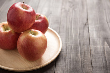 Fresh ripe red apples on dish wooden background