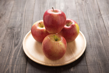 Fresh ripe red apples on dish wooden background