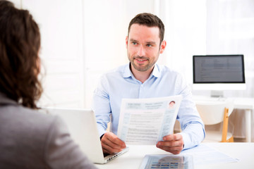 Fototapeta premium Young attractive employer analysing resume of woman