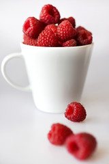 red raspberry in white cups on white background