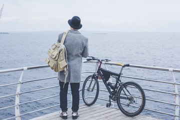 Obraz premium handsome young hipster guy in hat with bike looking at the sea