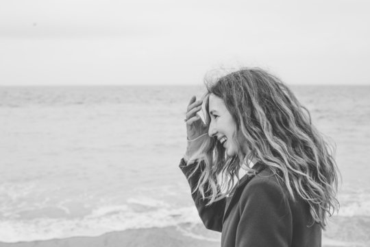 blonde curly girl smiling having fun calm sea black and white