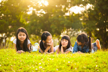 Little asian girls laying on the green grass under sunlight