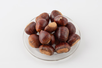 Pile of chestnuts on a plate on white background