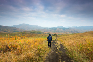 Man climbing a hill with colorful clouds