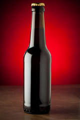 Bottle of beer on a stone table over red background