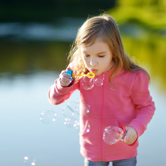 Funny lovely little girl blowing soap bubbles