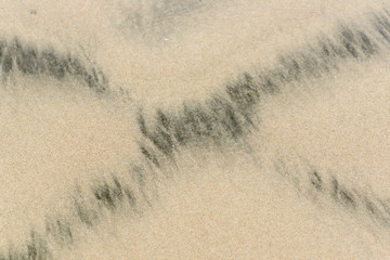 ein schwarzes Kreuz im Strandsand