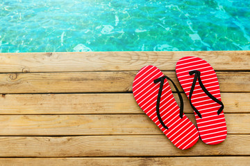Flip flops on wooden deck over water background